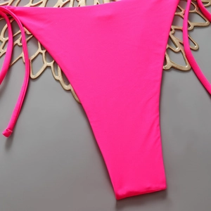 Detail of neon pink bikini bottom with side ties and high-stretch quick-dry fabric texture