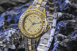 Detail of luxury gold and silver watch with crystals on a textured rock surface