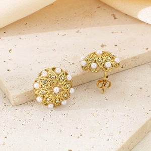 Close-up of vintage hollow flower gold stud earrings with white pearls and rhinestones
