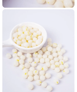 Detailed macro view of miniature PVC lotus seeds in a white ceramic spoon for DIY crafts