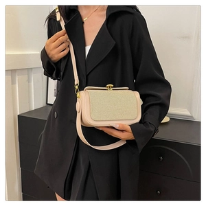 Detail of beige crossbody bag with woven texture flap and elegant gold hardware accent