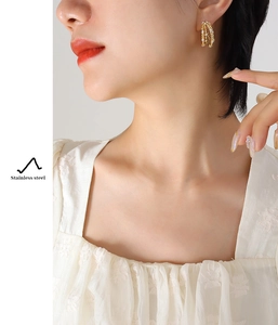 Close-up of gold stainless steel four-layer C-shaped earrings with zircon inlay