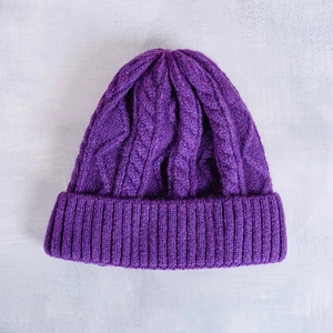 Close-up of purple cable-knit pattern and ribbed cuff on a soft winter beanie hat