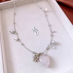 Elegant beaded necklace with pink strawberry pendant and pearls on soft velvet tray