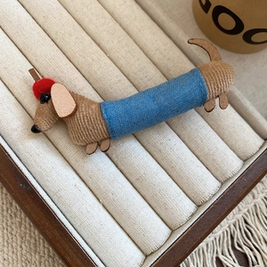 Detailed close-up of a handmade dachshund fabric hair clip with a red hat and denim clothes