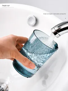 Close-up of modern blue transparent mouthwash cup being filled with water in a sink