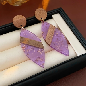 Détail des boucles d'oreilles en forme de feuille en bois et résine violette avec dorure