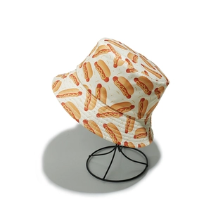 Detail shot of a cream bucket hat featuring vibrant cartoon hot dog prints on canvas fabric