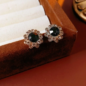 Macro shot of gold vintage flower earrings with black stone and diamonds on velvet