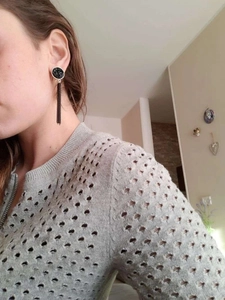 Detailed view of long black tassel earrings with vintage rhinestone studs on person