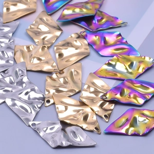 Détail de breloques géométriques martelées en métal doré argenté et couleurs arc-en-ciel