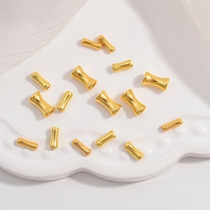 Macro shot of gold bamboo joint beads and spacers on a white ceramic plate for DIY jewelry