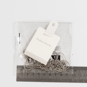 Detail of silver snake chain necklace with beads next to a ruler for size reference