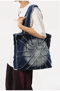 Detail of large denim tote bag featuring vintage patchwork design and frayed edges on model