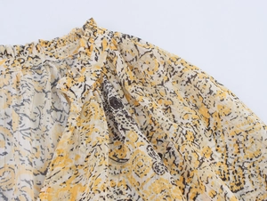 Detail of ruffled neckline and yellow floral print on lightweight chiffon shirt