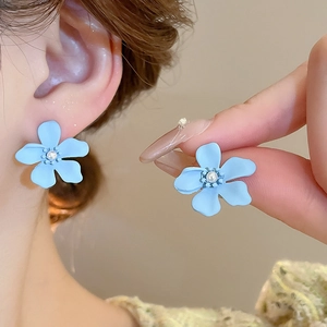 Détail des boucles d'oreilles fleur bleue avec perle portée par un mannequin