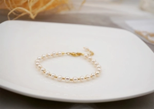 Detail of handmade freshwater pearl bracelet with golden beads and adjustable lobster clasp