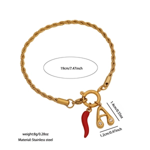 Detail of gold twisted chain bracelet with red chili pendant and rhinestone letter A