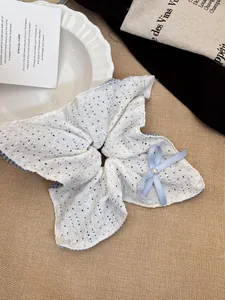 Detail of white lace hair scrunchie with blue polka dots, ribbon bow and pearl bead