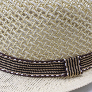 Close-up of finely woven straw hat texture with striped ribbon detail for summer