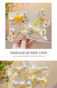 Close-up of hair bow clip set with colorful polka dots and yellow satin textures
