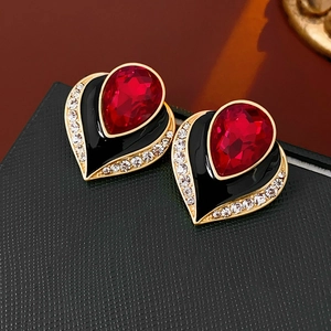 Close-up of vintage gold heart earring with red teardrop stone and black enamel