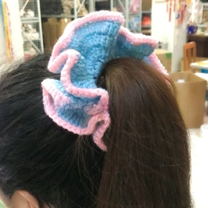Close-up of a blue and pink ruffled knit hair scrunchie worn on a ponytail
