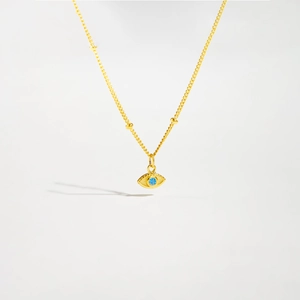 Macro detail of gold S925 silver necklace featuring evil eye pendant with blue gemstone