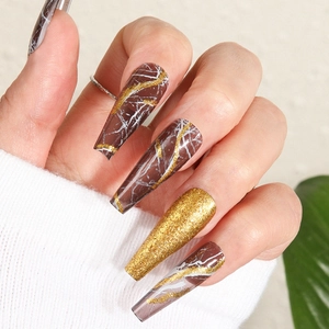 Long stiletto press-on nails featuring brown marble patterns and gold glitter accents