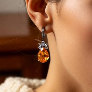 Detail shot of vintage orange teardrop zircon earring with petal accents and black base