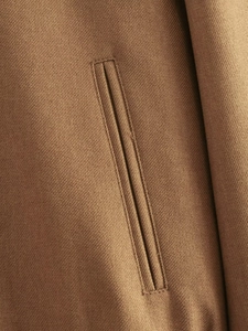 Detailed macro view of the brown twill fabric and welt pocket craftsmanship of the jacket