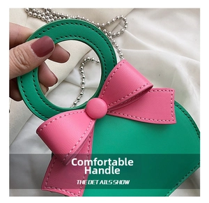 Close-up of contrast color mini bag with large pink bow and silver beaded chain strap