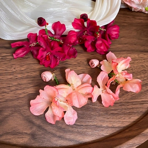 Detail of fabric flower earrings with crystal tassels in wine red and pink gradient