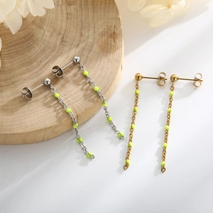 Detail of bohemian gold and silver chain earrings with vibrant neon beads on wood