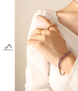 Detail of stainless steel jewelry set featuring purple zircon stone bracelet and golden rings