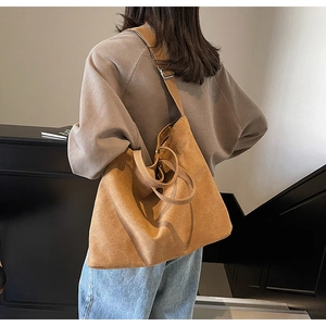Brown suede tote bag shown on shoulder highlighting large capacity and vintage texture