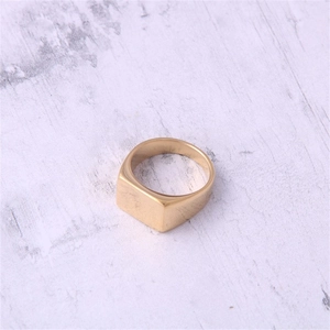 Close-up of a minimalist square signet ring in polished gold finish on wood