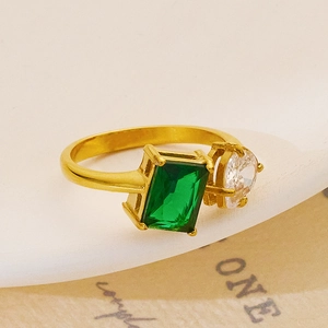 Detail view of gold ring with emerald-cut green stone and round white zircon inlay