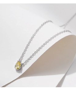 Close-up of a pear-cut yellow gemstone pendant on a fine silver s925 chain necklace