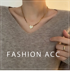 Close-up of golden heart pendant necklace with white inlay on cable chain for women