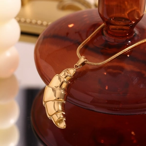 Close-up of 18K gold-plated croissant pendant necklace on fine snake chain jewelry