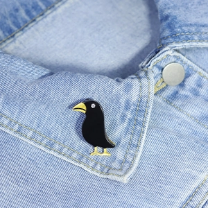 Handmade black crow acrylic brooch pin with gold beak on denim jacket lapel
