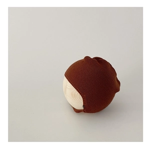Close-up of baby knit bonnet in dark caramel with soft texture on wooden display stand