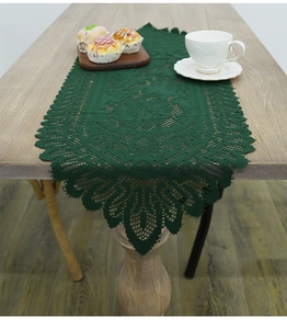 Close-up of green crochet lace table runner with hollow patterns on wooden table