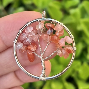 Macro shot of handmade Tree of Life pendant with orange and pink natural small stones