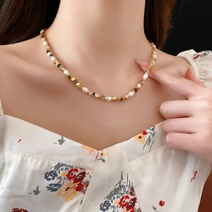 Close-up of freshwater pearl and gold chain necklace worn on a woman's collarbone