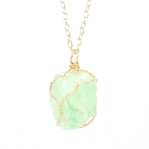 Detail of light green natural crystal stone pendant with gold wire wrapped by hand