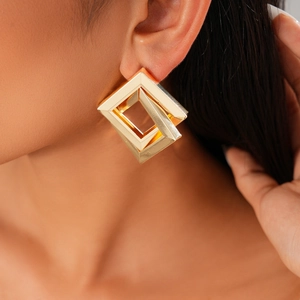 Detailed close-up of gold geometric square earrings with an interlocking frame design