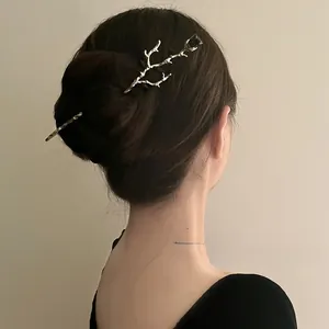 Detail of silver vintage metal hair pin with tulip bud on a minimalist wooden branch