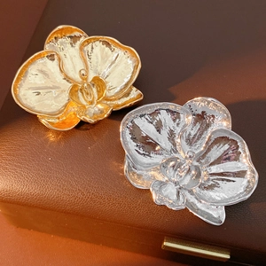 Macro detail of orchid brooches in gold and silver finish with textured metallic petals
